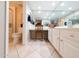Bright bathroom featuring a mirrored wall, white cabinetry, and a cozy vanity area with a decorative chair and tile flooring at 17404 N 99Th Ave # 126, Sun City, AZ 85373