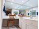Bright bathroom featuring a mirrored wall, white cabinetry, and a cozy vanity area with a decorative chair and tile flooring at 17404 N 99Th Ave # 126, Sun City, AZ 85373