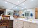 Bright bathroom featuring a mirrored wall, white cabinetry, and a cozy vanity area with a decorative chair and tile flooring at 17404 N 99Th Ave # 126, Sun City, AZ 85373