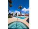 A swimming pool and jacuzzi with tall palm trees, residential buildings, lounge chairs and patio umbrellas at 17404 N 99Th Ave # 126, Sun City, AZ 85373