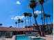A swimming pool featuring palm trees, residential buildings, lounge chairs and patio umbrellas at 17404 N 99Th Ave # 126, Sun City, AZ 85373