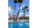 A swimming pool with ladder, tall palm trees, residential buildings, lounge chairs and patio umbrellas at 17404 N 99Th Ave # 126, Sun City, AZ 85373