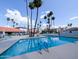 A swimming pool with ladder, tall palm trees, residential buildings, lounge chairs and patio umbrellas at 17404 N 99Th Ave # 126, Sun City, AZ 85373