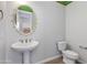 Charming powder room with pedestal sink, decorative mirror, and tiled flooring at 24533 N 19Th Ter, Phoenix, AZ 85024