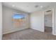 A well-lit bedroom with neutral carpet, a view from the window, and an open doorway at 24533 N 19Th Ter, Phoenix, AZ 85024