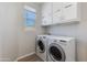 Laundry room featuring full size washer and dryer with overhead storage cabinets at 24533 N 19Th Ter, Phoenix, AZ 85024
