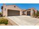 Spacious driveway leading to a three-car garage with desert landscaping at 26161 W Siesta Ln, Buckeye, AZ 85396