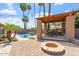 Backyard with built-in BBQ and barstool seating, surrounded by patio, pool and beautiful palm trees at 2727 W Ocaso Cir, Mesa, AZ 85202