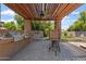 Inviting outdoor kitchen with built-in grill under a shaded pergola and ceiling fan at 2727 W Ocaso Cir, Mesa, AZ 85202