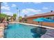 This backyard features a sparkling pool surrounded by rock accents and tall palm trees at 2727 W Ocaso Cir, Mesa, AZ 85202