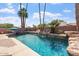 Beautiful backyard swimming pool with rock waterfall features surrounded by lush landscaping at 2727 W Ocaso Cir, Mesa, AZ 85202