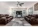 Spacious living room featuring plush leather sofas, shutters, a contemporary ceiling fan, and modern decor at 32096 N 132Nd Dr, Peoria, AZ 85383