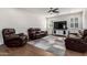 Comfortable living room with leather seating, tile flooring, plantation shutters, and a neutral color scheme at 32096 N 132Nd Dr, Peoria, AZ 85383