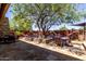 Charming patio area with shade tree, comfortable seating, and stone flooring, perfect for relaxation at 32096 N 132Nd Dr, Peoria, AZ 85383