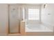 Bright bathroom featuring a bathtub, glass shower, and a window for natural light at 3545 W Glass Ln, Phoenix, AZ 85041