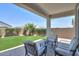Relaxing backyard with a covered patio, seating area, artificial turf, and lush landscaping at 38144 W San Clemente St, Maricopa, AZ 85138