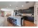 Spacious kitchen with an island with seating and a gray speckled granite countertop, dark cabinets, and modern appliances at 38144 W San Clemente St, Maricopa, AZ 85138