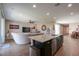 Open floor plan featuring a kitchen island overlooking the living room with a ceiling fan, a sofa, and a tv at 38144 W San Clemente St, Maricopa, AZ 85138