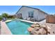 Backyard pool featuring a rock waterfall, surrounded by lush greenery and patio with lounge seating at 38144 W San Clemente St, Maricopa, AZ 85138