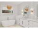 This bright bathroom offers a freestanding tub and double vanity, enhanced by geometric wallpaper and natural light at 3924 E Roma Ave, Phoenix, AZ 85018