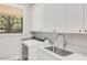 Bright laundry room with white cabinetry, stainless sink, and modern washer and dryer at 3924 E Roma Ave, Phoenix, AZ 85018