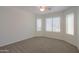 Bright bedroom with carpet, ceiling fan, and multiple windows for natural light at 40468 W Sanders Way, Maricopa, AZ 85138