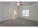 Spacious main bedroom featuring neutral walls, carpet flooring, ceiling fan, and ample natural light from the window at 40468 W Sanders Way, Maricopa, AZ 85138