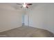 Bright main bedroom with neutral carpet, a ceiling fan, and a doorway leading to another room or closet at 40468 W Sanders Way, Maricopa, AZ 85138