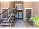 Close-up of condo entryway with metal stairs, white doors, and desert landscaping at 5230 E Brown Rd # 114, Mesa, AZ 85205