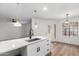 Bright kitchen features a stainless sink, white cabinets, quartz countertop, stylish lighting, and door to yard at 5230 E Brown Rd # 114, Mesa, AZ 85205