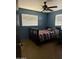 This bedroom has a ceiling fan, natural light, and a colorfully striped comforter on a bed with a black frame at 608 W 2Nd Pl, Mesa, AZ 85201