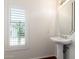 Well-lit powder room featuring pedestal sink, window with plantation shutters and tile floors at 6510 S Hazelton Ln # 101, Tempe, AZ 85283