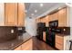 Well-lit kitchen featuring wood cabinets, black appliances, and granite countertops at 6510 S Hazelton Ln # 101, Tempe, AZ 85283
