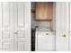 Laundry area with a washer and dryer, enclosed by bi-fold doors and shelving above at 6510 S Hazelton Ln # 101, Tempe, AZ 85283