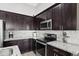Well-equipped kitchen showcasing stainless steel appliances, dark wood cabinetry, and sleek backsplash at 6623 S 23Rd Dr, Phoenix, AZ 85041