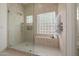 Luxurious shower featuring neutral tile, glass enclosure, built-in bench, and unique glass block window at 7152 E Night Glow Cir, Scottsdale, AZ 85266
