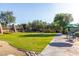 A lush green lawn area in a community with mature trees and a seating area with an umbrella at 7152 E Night Glow Cir, Scottsdale, AZ 85266