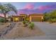 Charming tan home featuring desert landscaping and a three-car garage at sunset at 7152 E Night Glow Cir, Scottsdale, AZ 85266