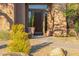 Elegant front entrance with a wood door, potted plants, and desert landscaping at 7152 E Night Glow Cir, Scottsdale, AZ 85266