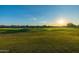Scenic golf course view with lush green grass, water feature, and stunning sunset in the background at 7152 E Night Glow Cir, Scottsdale, AZ 85266
