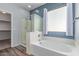 Well-lit bathroom featuring a soaking tub, glass shower, and walk-in closet at 7169 W Lamar Rd, Glendale, AZ 85303