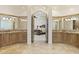 Primary bathroom with double vanity, granite countertops, and an arched entry to main bedroom at 7640 E Poinsettia Dr, Scottsdale, AZ 85260