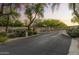 A secure, gated entrance with mature trees and manicured landscaping provides privacy and curb appeal at 7640 E Poinsettia Dr, Scottsdale, AZ 85260