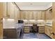 Well-lit laundry room with wood cabinets, granite countertops, and modern washer at 7640 E Poinsettia Dr, Scottsdale, AZ 85260