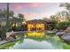 Exterior evening view of a pool and spa with mature trees, desert landscaping, and building with outdoor kitchen at 7640 E Poinsettia Dr, Scottsdale, AZ 85260