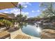 A backyard pool with desert landscaping, lounge chairs and tables, and a rock waterfall and spa at 7640 E Poinsettia Dr, Scottsdale, AZ 85260