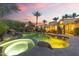 A luxurious backyard at dusk with a pool and spa, beautiful landscaping, and exterior living area at 7640 E Poinsettia Dr, Scottsdale, AZ 85260