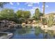 A resort-style backyard pool with rock waterfall, mature landscaping, and a beautiful desert setting at 7640 E Poinsettia Dr, Scottsdale, AZ 85260