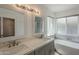 Bright bathroom features a double vanity, modern fixtures, and a soaking tub with natural light from the window at 807 E San Remo Ave, Gilbert, AZ 85234