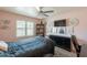 A comfy, light pink bedroom with a ceiling fan, decorative art, and large window at 8787 E Mountain View Rd # 1110, Scottsdale, AZ 85258